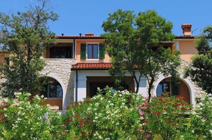 Experience the charm of a Mediterranean-style villa with arched windows and doors, surrounded by lush flowering plants.