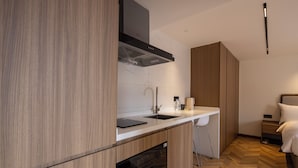 A modern kitchen with wooden cabinetry, a black range hood, and a white countertop. - LN Residece Taojin (Guangzhou)
