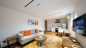 A modern living room with a sofa, coffee table, and a TV mounted on the wall. - LN Residece Taojin (Guangzhou)