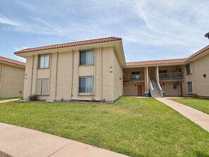 A multi-story apartment building with a flat roof, a central staircase, and a well-maintained lawn. - Beautiful view of the beach from the balcony, newly remodeled with new furniture (Port Aransas)