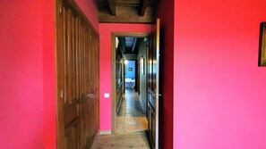 A narrow hallway with wooden doors on the left and a blue room at the end. - Casa Vacacional Ekilore (Poo De Llanes)