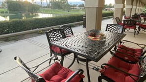 Eine Außenpatio mit Tisch und Stühlen, Blick auf einen Golfplatz und ein Gewässer.