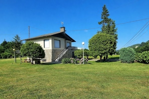 A two-story house with a stone facade, a wooden deck, and a well-maintained lawn. - Villa Mauro Vivienda Vacacional (Naves (Posada Llanes))