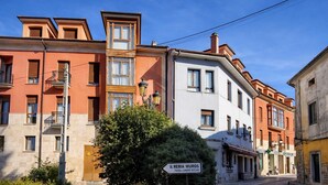 Une vue de rue avec des bâtiments dotés de balcons, une enseigne indiquant « Il Reria Muros », et un petit arbre au premier plan.
