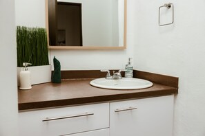 Ein Badezimmer mit einem weißen Waschbecken, einem Spiegel und einer Holzauslage.