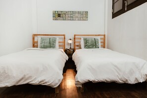 Ein Zimmer mit zwei Betten, einem Wandbild und einem Nachttisch mit Lampe.