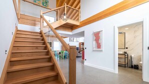 A wooden staircase with a glass railing leading to a mezzanine. - Villa Vacacional La Raizona (Pancar)