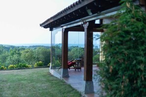 Ein überdachter Außenbereich mit Tisch und Stühlen mit Blick auf eine üppige Landschaft.