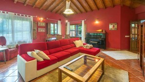 A cozy living room with a red sofa, a wooden coffee table, and a piano. - Villa Las Ardillas con Piscina (Cardoso (Llanes))
