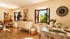 A cozy dining area with a wooden table, chairs, a white cabinet, and a wall-mounted clock. - Casa La Venta de Pedro (Ribadesella)