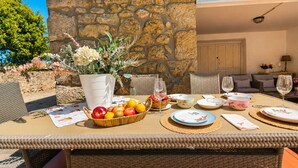 A wicker table set for dining with a fruit bowl, plates, and a vase of flowers. - Casa La Venta de Pedro (Ribadesella)