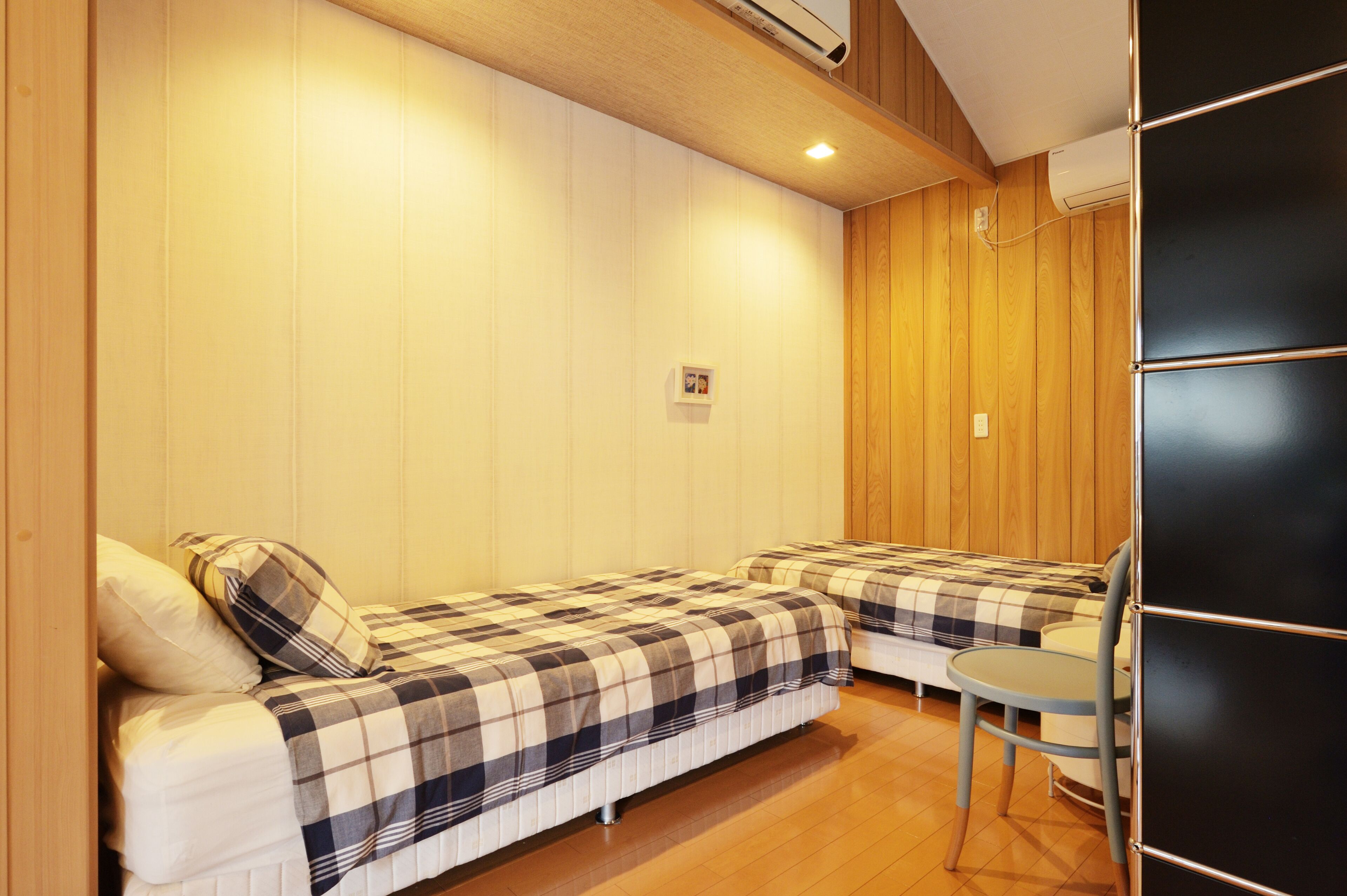 A room with two beds, a small table, and a wooden floor.