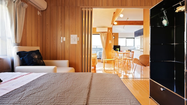 A modern room with a bed, a sofa, and a dining area with chairs. - SAYA Suite Kishinosato Annex (Osaka)