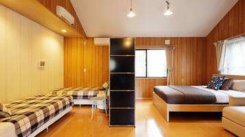 A room with wooden panel walls, a bed, a sofa, a small table, and a black shelving unit.