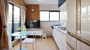 A modern kitchen with a TV, dining table, chairs, and a small stool. - SAYA Suite Kishinosato Annex (Osaka)