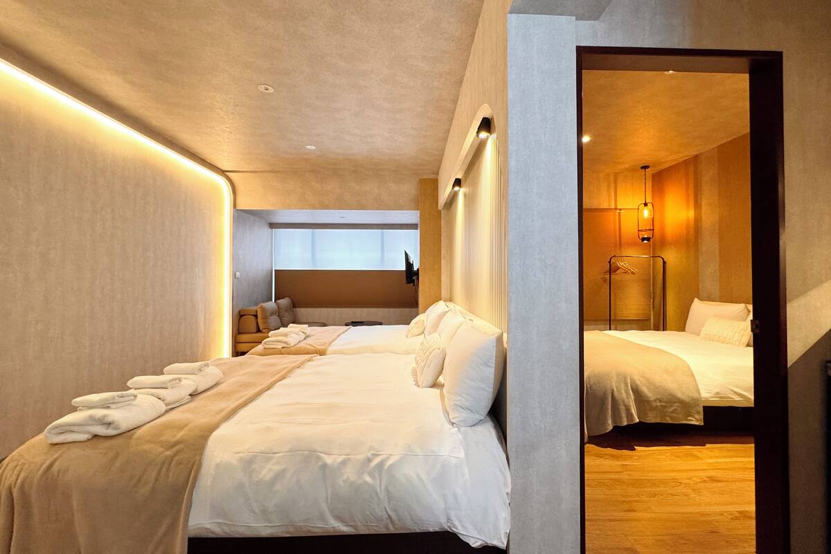 A modern hotel room with a large bed, a seating area, and a mirror reflecting the room.