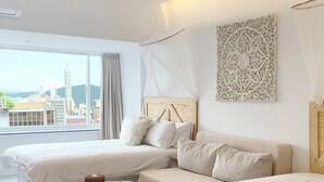 A hotel room with two beds, a small round table, and a view of the cityscape. - Urban Abode Apartment 1 (Taipei)