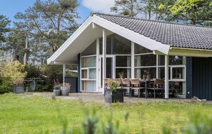 A house with a large glass window area, a dining table with chairs, and a garden with potted plants. - 4 bedroom beautiful home in Kalundborg (Kalundborg)