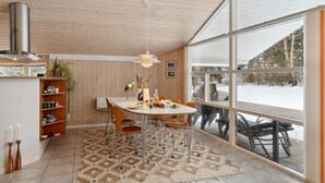 Une cuisine moderne avec un coin repas, de grandes fenêtres et une vue sur un paysage enneigé.