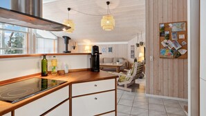Une cuisine moderne dotée d’une cuisinière intégrée, de meubles en bois et de luminaires suspendus.