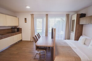 A modern hotel room with a wooden dining table, a sofa, a TV, and a kitchen area. - Comfort Studio with Patio (Visoko)