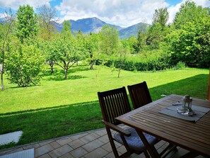 A patio with a table and chairs overlooking a lush garden and mountains. - Comfort Studio with Patio (Visoko)