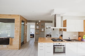 A modern kitchen with white cabinets, a wooden countertop, and a built-in oven.
