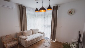 A living room with a sofa, a chair, a geometric coffee table, and a television. - Panoramic apartment with Terrace (Visoko)