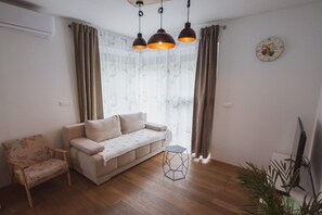 A living room with a sofa, a chair, a geometric coffee table, and a television. - Panoramic apartment with Terrace (Visoko)