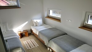 A dormitory room with three single beds, a small wooden nightstand, a window with a view of trees, and a light switch on the wall. - Panoramic apartment with Terrace (Visoko)