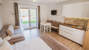 Ein modernes, helles Zimmer mit einer Couch, einem Esstisch und einer Küchenzeile.