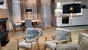 Ein modernes Wohnzimmer mit Kamin, Essbereich und einer Küche mit Flachbildfernseher.