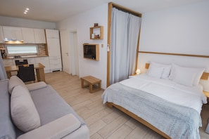 A modern hotel room with a bed, a sofa, a small table, and a kitchenette. - Classic Studio with Patio (Visoko)