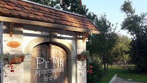 Ein rustikales Gebäude mit einer Holztür und einem Schild, auf dem 'Pr'Fik apartments' steht.
