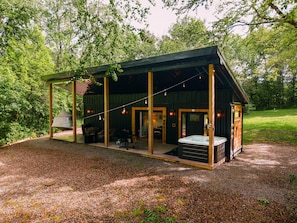 A rustic cabin with a covered patio, a hot tub, and a dining area.