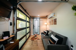 A compact living space with a sofa, a coffee table, and a desk with a computer.