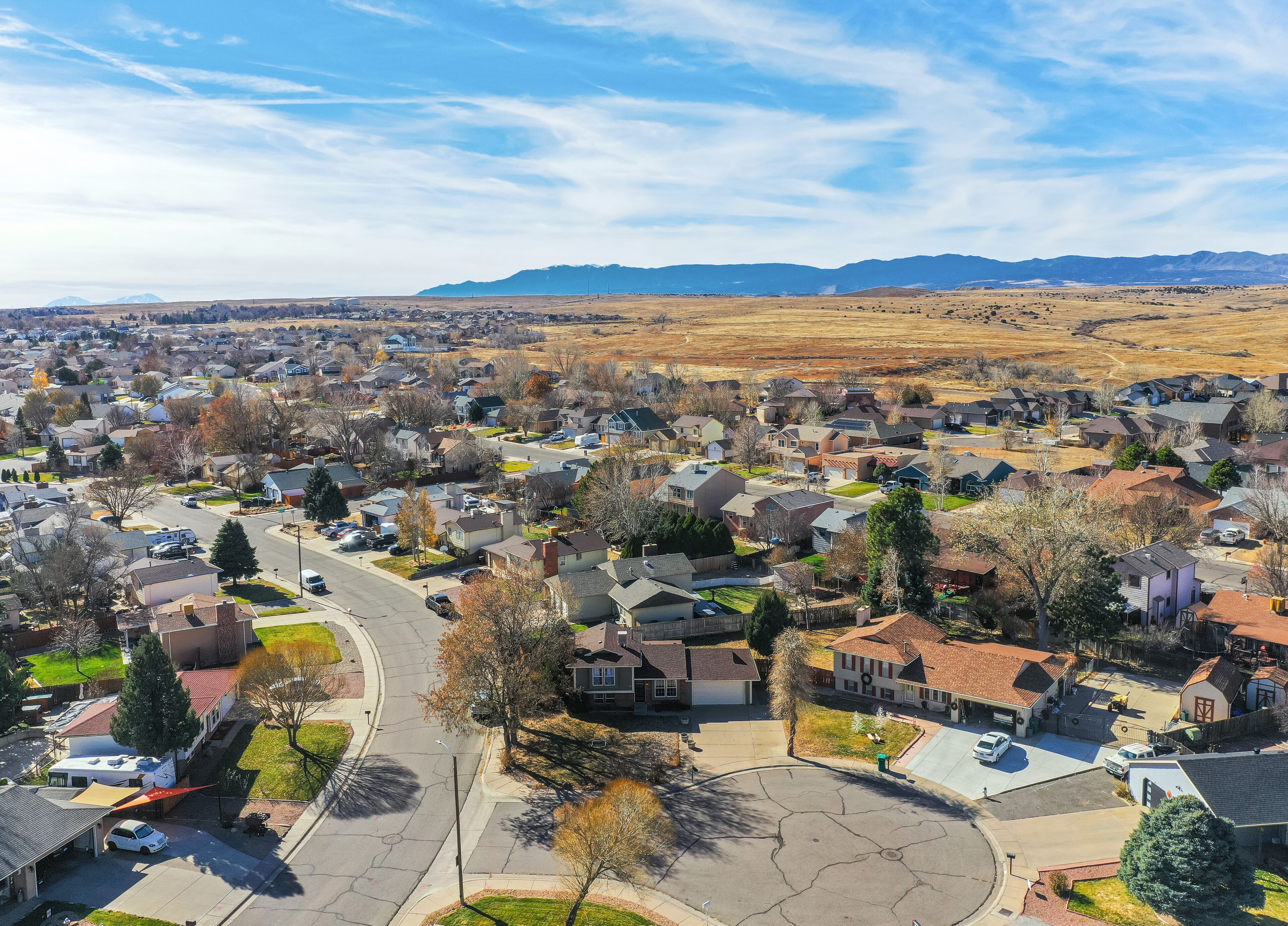 A suburban neighborhood with houses, streets, and a mountain range in the background.