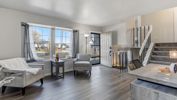 A spacious living area with a sofa, armchair, and dining table, a staircase, and a view of the outdoors. - Pueblo Place (Pueblo)