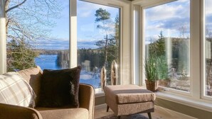 A cozy room with a view of a lake and forest. It includes a sofa, a small chair, and a table. - 3 bedroom gorgeous home in Ullared (Ullared)