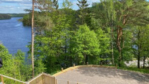 A wooden deck with a railing overlooking a lake, surrounded by dense trees. - 3 bedroom gorgeous home in Ullared (Ullared)