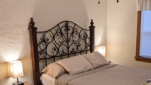 A bed with a quilted bedspread, two pillows, a bedside table with a lamp, and a decorative metal headboard. - The Highland View House (Somerset)
