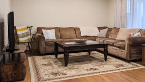 A living room with a brown sofa set, a wooden coffee table, a television on a stand, and a patterned rug. - The Highland View House (Somerset)