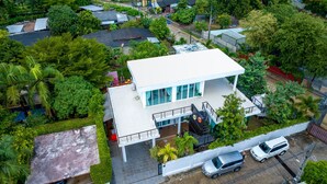 Une maison moderne à deux étages, dotée d’un toit plat, de grandes fenêtres et d’un balcon.