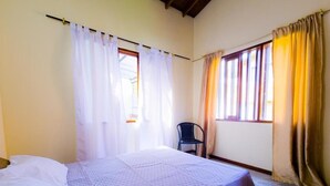 A bedroom with a bed, a chair, and curtains. - Hostal - Casa Rionegro (Rionegro)