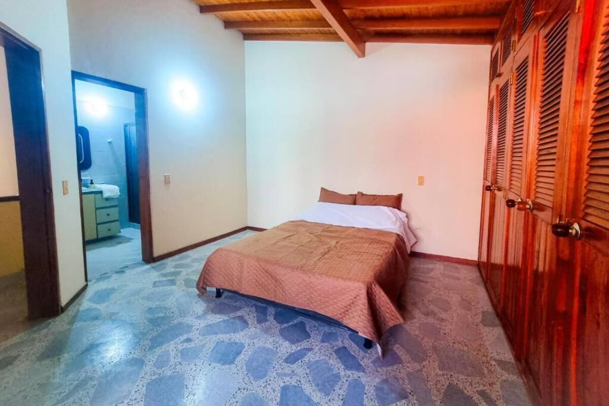 A bedroom with a bed, a wardrobe, and a door leading to another room.