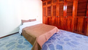 A bedroom with a bed, a wooden wardrobe, and a patterned floor. - Hostal - Casa Rionegro (Rionegro)