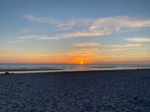 A beach with a sunset over the ocean.