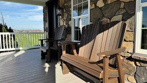 A wooden deck with Adirondack chairs and a stone wall. - Charming Farmhouse In Quarryville,PA

 (Quarryville)