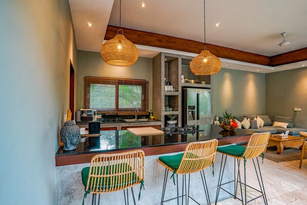 A modern kitchen with a central island, bar stools, and pendant lighting.