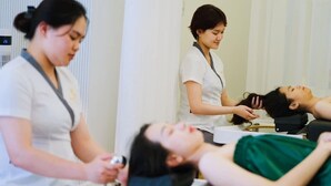 A clinical setting with a person lying on a treatment table receiving a procedure from a practitioner. - Kamy Phuong House and Spa (Xuan Huong - Da Lat)